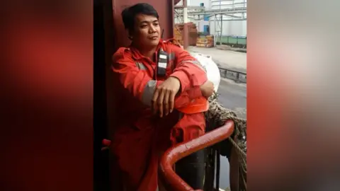 PA Media Photograph of Mark Angelo Pernia issued by the Crown Prosecution Service. He is wearing orange overalls and dark hair and is pictured on a ship.