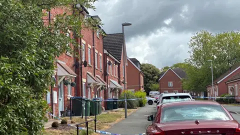 A residential road with police cordon tape going across the street