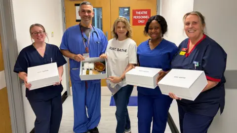 Just.Bathe Steph Alger with hospital staff holding boxes of the bathing kits. 