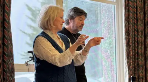 WAOS A woman and man stood next to each other. The woman, left, is gesticulating with her hands.