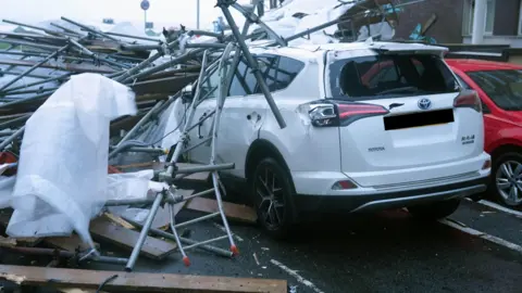 Eddie Mitchell A white car is damaged by scaffolding. 