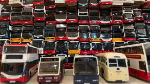 Leeds City Museum More than 50 model busses in a variety of colours stacked in rows