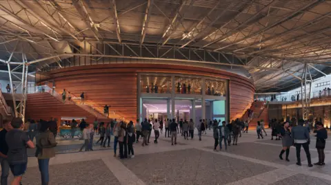 Government of Jersey Large indoor public atrium with a high industrial-style ceiling and metal beams. A curved, wood‑clad structure sits at the centre, with staircases leading to upper levels. Crowds of people walk, talk, and gather around the open space, which is warmly lit.