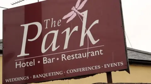 ROBBIE WEST/BBC A close-up of the Park Hotel sign, which is a burgundy colour, and has "The Park. Hotel. Bar. Restaurant" printed on it in a white font.