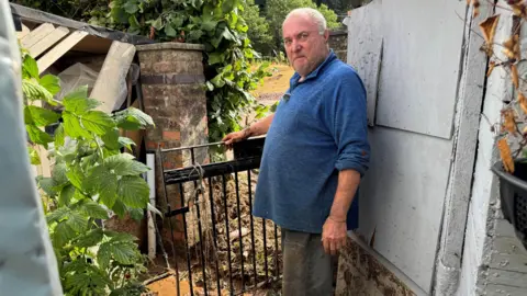 Steven Mordecai stood at the gate in his back garden following the flooding.