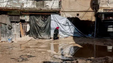 AFP File photo showing a Palestinian woman walking past a large puddle in Jenin refugee camp in the occupied West Bank (18 January 2025)