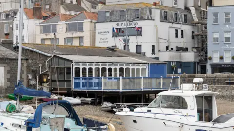 Guernsey Ports A picture of the former restaurant at the Victoria (Crown) Pier in Guernsey. The building is empty with a glass conservatory overlooking the harbour. There are 