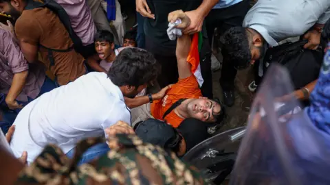 Reuters A man is held by the arms by onlookers, his eyes roll back in his head and he looks as if he is losing consciousness 