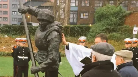 A memorial in Stockport depicts James Conway paddling. The photograph is taken at the unveiling of the statue in 2017, attended by local dignitaries and current serviceman.
