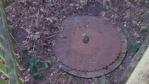 Image shows the serrated circular cover of a disused well  