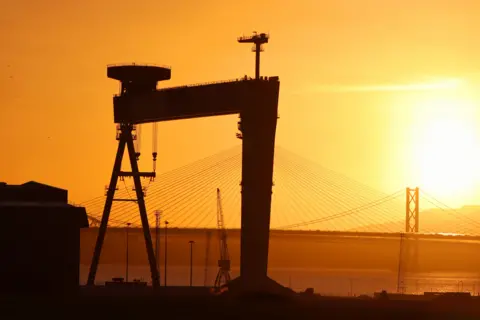 Jimmy Mason Sunrise image showing the shadow of the Goliath crane at Rosyth dockyard with the Forth bridges in the distance