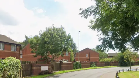 Modern red brick houses and trees line Galligreaves Way in Blackburn as it curves round towards Heatley Close.
