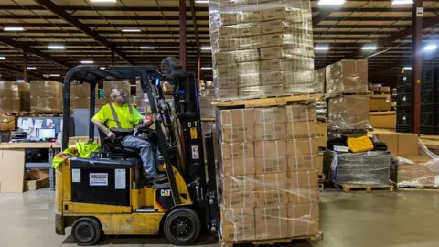 A person in a yellow reflective vest mans a forklift piled high with boxes of toys at the Duncan Toy Company in the firm's warehouse in Columbus, Indiana, on April 16, 2025. 