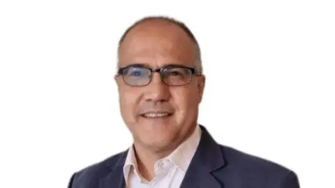 Khalid Razzaq Khalid Razzaq with short grey hair wearing a blue jacket