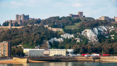 View from the western docks of Dover Castle and White Cliffs and hotel on the beach