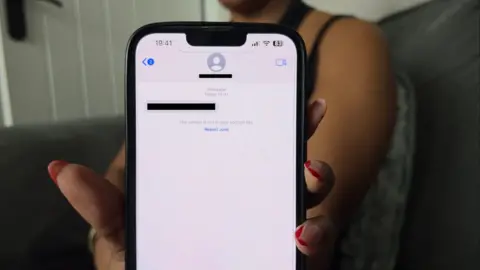 Woman holds iPhone up to the camera to show redacted messages she allegedly received from a scam locksmith