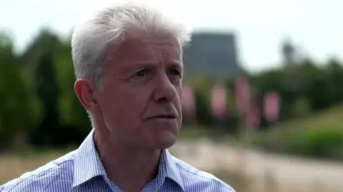 Shawn Dawson, a man with grey hair, wearing a vertically-striped blue and white shirt