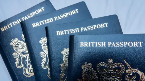 Getty Images Four blue British passports. They have a gold logo on and gold capital letters reading "British passport". 