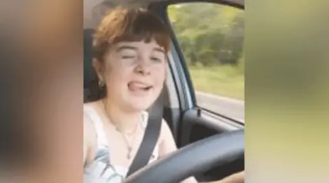 Norfolk Constabulary A selfie image of a young woman winking at the camera with her tongue out while driving 