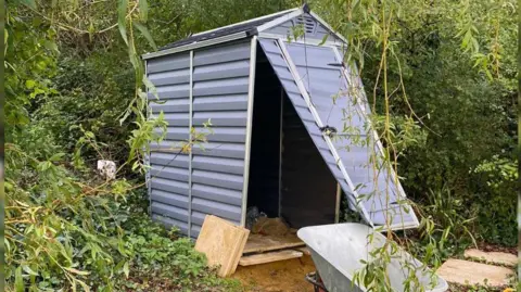 Kaye Lax The front door of a small storage shed is partially ripped off.