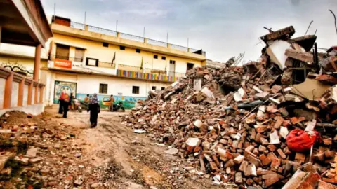 Vivek Singh People standing outside Javed Mohammad's home in the Indian state of Uttar Pradesh after it was demolished