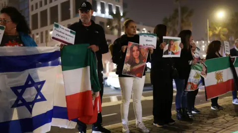 Reuters Eight protesters pictures holding the flags of Israel and pre-1979 Iran as well as a number of photographs and banners calling for Donald Trump to help. 