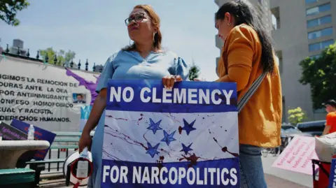 Demonstrators gathered outside the Manhattan federal court after the sentencing of former Honduran President Juan Orlando Hernandez Alvarado in June 2024 in New York, hold up a sign reading "no clemency for narcopolitics".