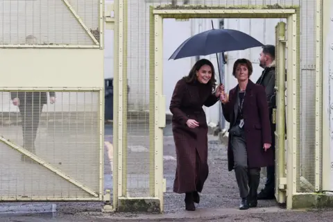 Reuters The Princess of Wales dikawal di dalam gerbang HMP Styal di Cheshire, berlindung di bawah payung.