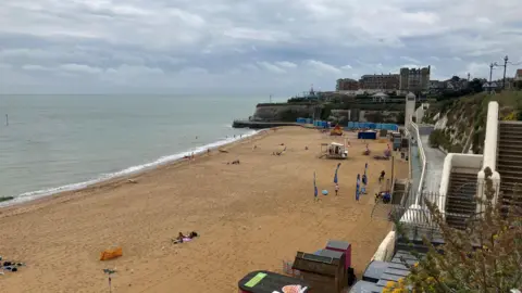 Simon Jones / BBC A beach with stairs to the right of it. The sky is blue and cloudy.