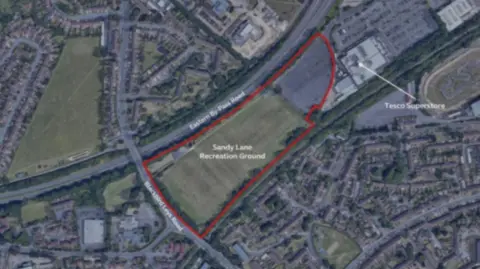 Oxford City Council An ariel view of the Sandy Lane Recreational Ground shows it is bordered by Oxford's Eastern By-Pass and a Tesco Superstore to the North. Another field, of a similar size, can be seen nearby, on the other side of the ring road. 