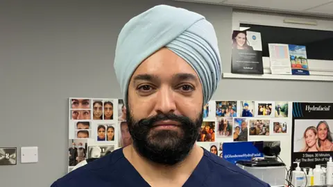 BBC A man wearing a blue uniform, looking directly at the camera.