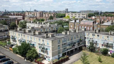 A social housing estate in London, 2018. There are several blocks of flats, grass and trees.