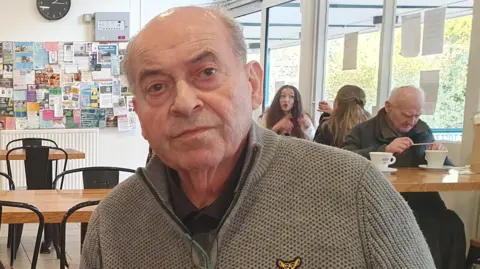 LDRS Alberto D'Auria in a jumper sat inside Parliament Hill Cafe. 