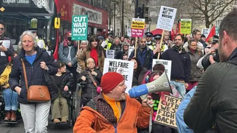 Handout People protesting about the welfare cuts through London with placards