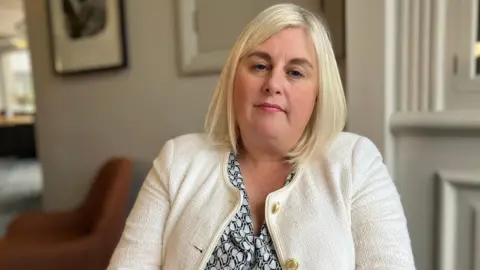 Michelle Welsh, sitting in a room, looking at the camera