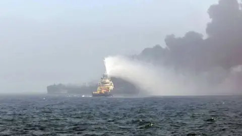 PA Media A lifeboat heading towards the site of the crash in the North Sea with a black cloud of smoke bilowing above one of the vessels.