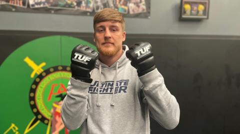 Paddy McCorry poses wearing The Ultimate Fighter gloves