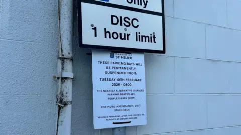 A sign on a lamppost, which says: "Parish of St Helier. These parking bays will be permanently suspended from Tuesday 10 February 20206 - 08.00. The nearest alternative disabled parking spaces are People's Park (80m). For more information visit sthelier.je. Vehicles remaining after this time will be removed at owner's expense."