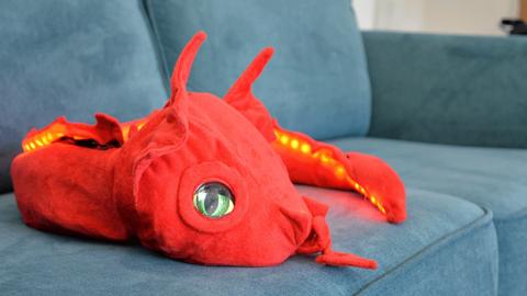Red robotic dragon curled up on a blue sofa