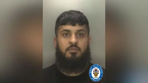 Jafir Nazir, a custody image of a man with a long beard who is wearing a black tshirt and looking directly at the camera