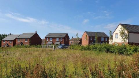 Red brick new-build properties with a field in front 