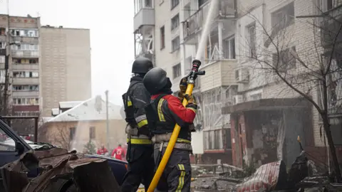 Getty Images petugas pemadam kebakaran memadamkan api di gedung perumahan yang rusak di pusat kota setelah penembakan Rusia pada 24 Maret 2025 di Sumy, Ukraina.