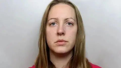 Custody image of Lucy Letby, who has long blonde hair and is wearing a red top.