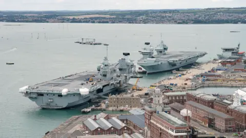 Aircraft carrier HMS Prince of Wales (top right) berths alongside aircraft carrier HMS Queen Elizabeth as it arrives at Portsmouth Naval Base.