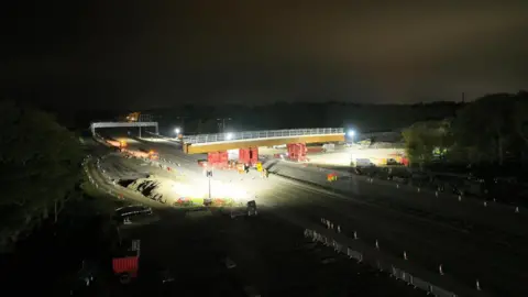 National Highways Workers install the new Clearmount bridge across the road at night