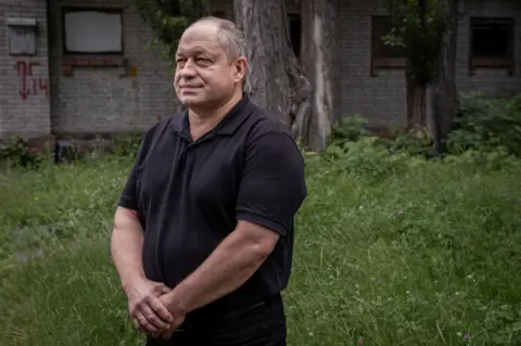Serii Dr. Andriichenko is located in the grassy field, wearing a black polo shirt, the hands came in front of him.