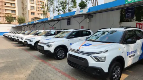 Cabs of ride-sharing company BluSmart seen on the road with its blue logo on the side