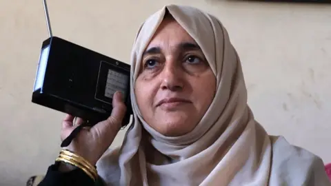 A Palestinian woman listens to radio in her house in Rafah in the southern Gaza Strip on December 19, 2023