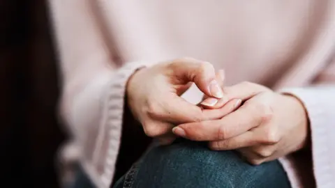 Getty Images Cropped shot of a woman sitting on a sofa and feeling anxious.