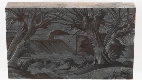 Subastadores Dominic Winter. Un bloque de madera grabado con una presa y algunos árboles. La superficie de impresión está oscura por la tinta.